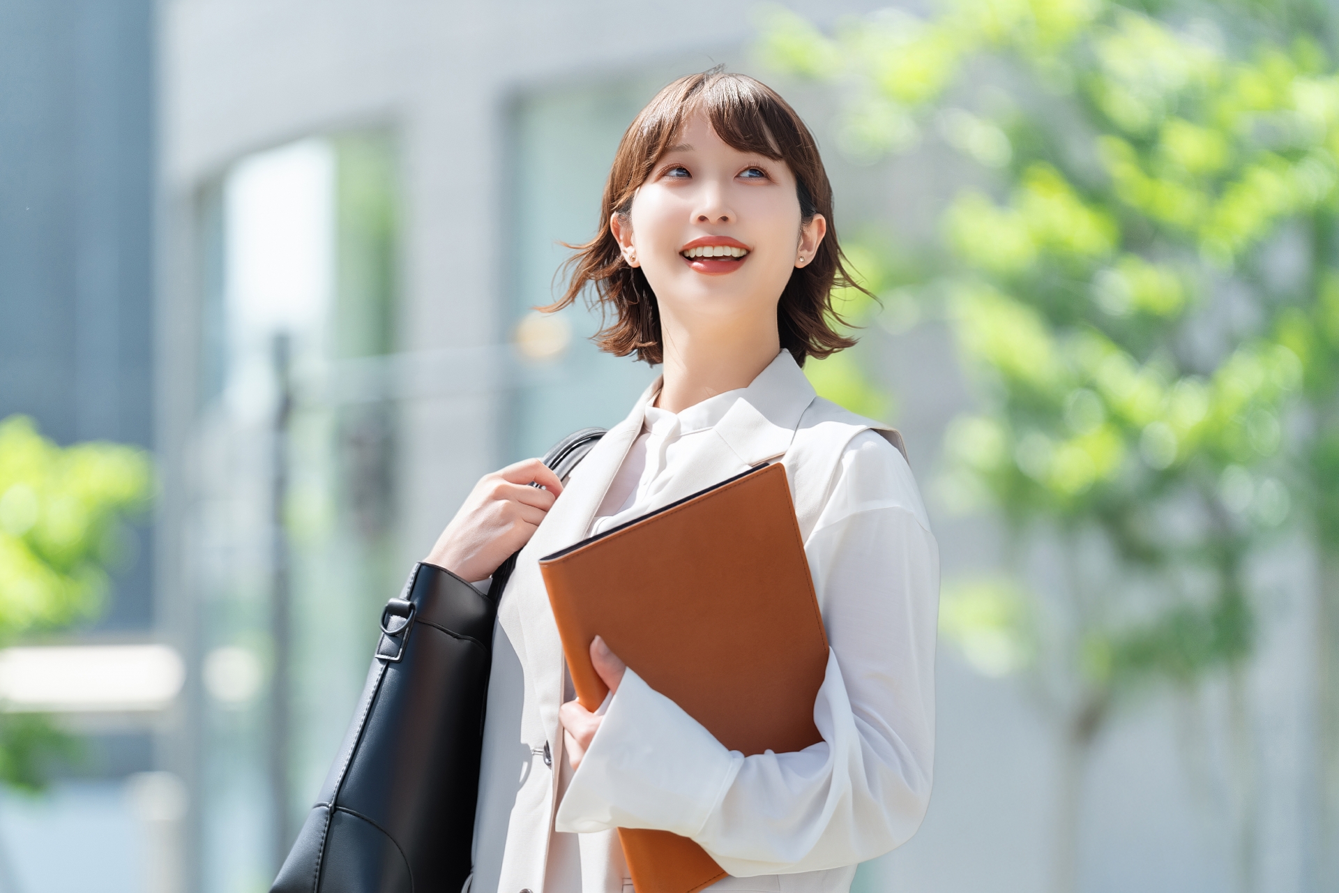 資料を手に、笑顔で前を向いて歩く女性